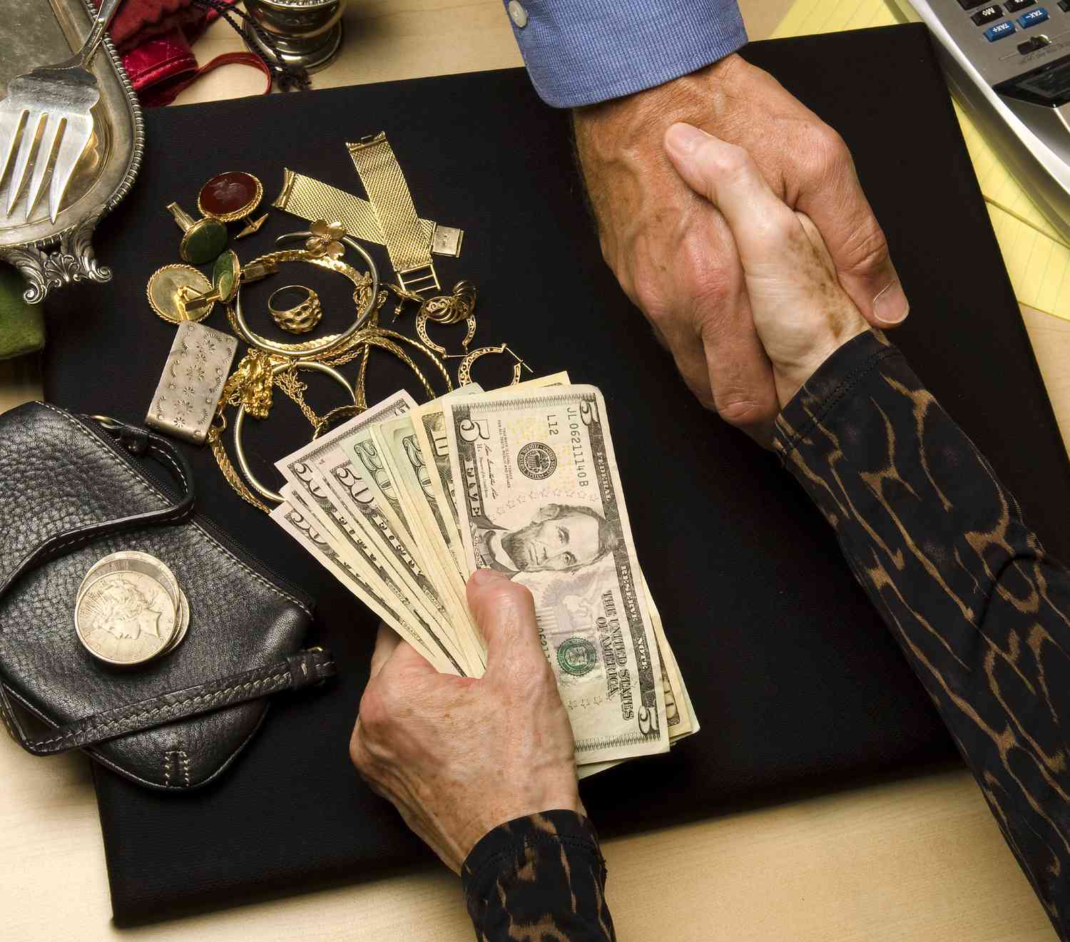 A Patriot Liquidating buyer shaking hands across a desk after paying cash for jewelry and personal valuables.